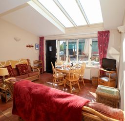 A living room with a sofa and dining area at Coachman's Cottage Ipswich