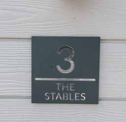 A sign displaying number 3 and The Stables at 3 The Stables Highbridge