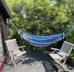 An outdoor space with a hammock and two wooden chairs at The Tree House in Nine Wells near Solva