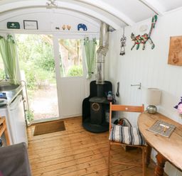 A kitchen with a stove and table at The Shephard Hut Nine Wells near Solva