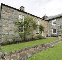 A stone house with a garden and pathway at Bwthyn Canol Llanfair