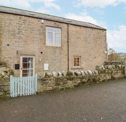A stone building with windows and a door at Watermill Cottage in North Charlton