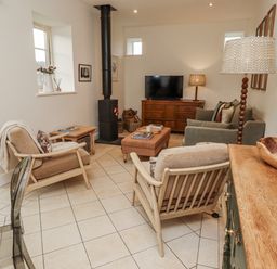 A living room with a television and seating area at Watermill Cottage in North Charlton