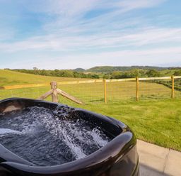 A hot tub with water and a scenic landscape at Defaid Cymreig Oswestry