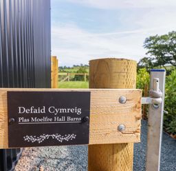 A sign on a wooden gate at Defaid Cymreig in Oswestry