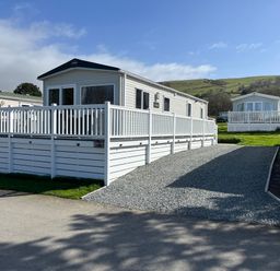 An outdoor view of a static caravan with decking at 8 Puffin Way in Llwyngwril