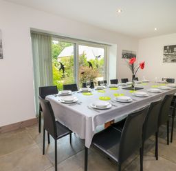 A dining room with a long table and chairs at Silver Copse in Frilford Heath Near Abingdon