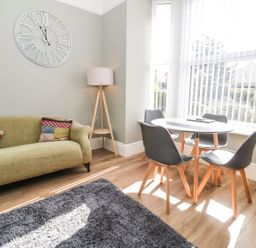 A living room with a clock on the wall at Flat 1A, Mona House in Conwy