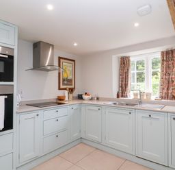 A kitchen with cabinets and appliances at Magdalen Cottage in Hook Norton