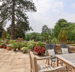 A garden with a table and chairs surrounded by plants at Magdalen Cottage in Hook Norton
