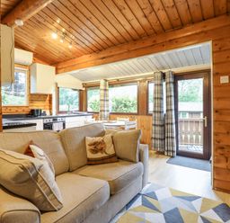 A living room with a sofa and kitchen view at Swn Yr Afon - No 333