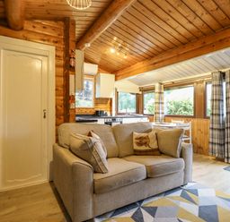 A living room with a sofa and kitchen area at Swn Yr Afon - No 333