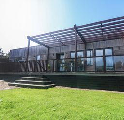 A wooden building with a deck and steps at Lodge 83, Gwel an Mor, Portreath