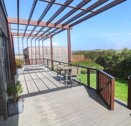 An outdoor deck area with seating and a view at Lodge 83, Gwel an Mor Portreath
