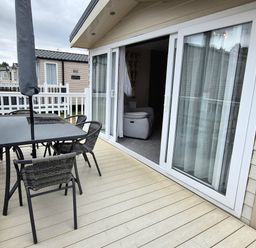 A balcony with an outdoor table and chairs at Fernwood Lodge in Fritton near Belton, Norfolk