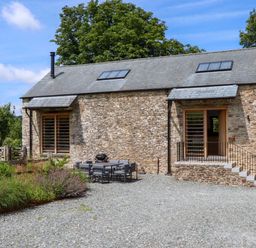An outdoor area with a stone wall and seating at Lower Walreddon Barn Tavistock