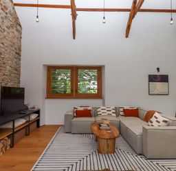 A living room with a stone wall and sofa at Lower Walreddon Barn Tavistock