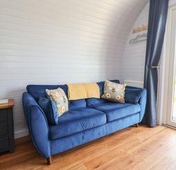 A snug room with a blue sofa and side table at Honeypot Hideaways - Manuka