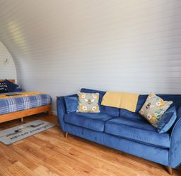 A bedroom with a bed and sofa at Honeypot Hideaways - Manuka