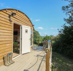 A wooden cabin with a deck and furniture at Squirrel's Drey Chapel Lawn near Clun