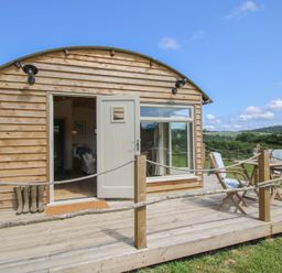 A wooden cabin with a deck and chairs at Owl's Hollow in Chapel Lawn near Clun