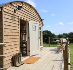 A wooden cabin with a deck and chairs at Owl's Hollow in Chapel Lawn near Clun