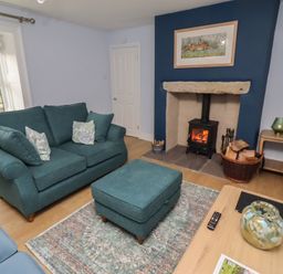 A living room with a sofa and fireplace at Linn Cottage in Hexham
