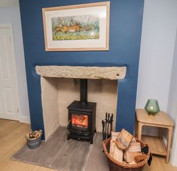 A living room with a fireplace and wood stove at Linn Cottage Hexham
