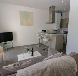 A living room with a television and kitchen area at Harbour View in Whitehaven