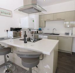 A kitchen with bar stools and appliances at Harbourside Apartments Whitehaven