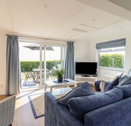 A living room with a television and a sliding door to the patio at Stella Maris in Torpoint