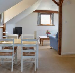 A living room with a table, chairs, sofa and television at The Stables in Budock Water near Falmouth