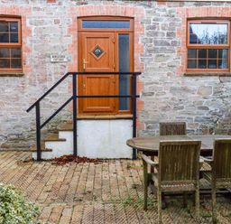 An outdoor area with a wooden table and chairs at Horseshoe Cottage in Falmouth
