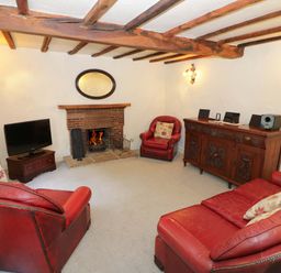A living room with a fireplace and leather furniture at Fern Cottage 
