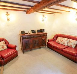 A living room with red furniture and a wooden cabinet at Fern Cottage