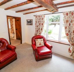 A living room with two red armchairs and a window at Fern Cottage in 