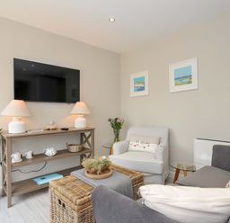 A living room with a television and seating area at Evelyn in Looe