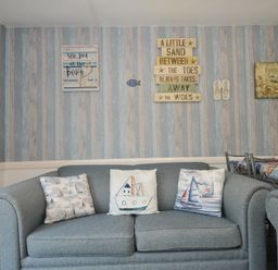 A living room with a blue sofa and decorative pillows at 13 Hillside in Bude
