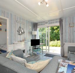 A living room with a television and sliding door at 13 Hillside in Bude