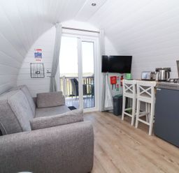 A living room with a sofa and TV at New Pod in Kilkhampton