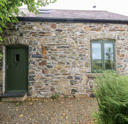 An exterior view of a stone cottage with a green door at The Dovecote near Fishguard