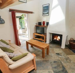 A living room with a sofa, coffee table, and television at The Dovecote in Llanychaer near Fishguard