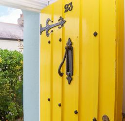 A yellow door with a handle and number 25 at Captains Cottage in Brixham