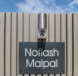 A sign with the name Noflash Malpal against a wooden wall in Bishop Sutton