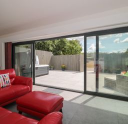A living room with a sliding glass door leading to an outdoor patio at Noflash Malpal in Bishop Sutton