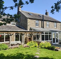 A house with a conservatory and garden at Bush Nook House in Brampton, Cumbria