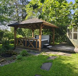 A garden with a wooden gazebo and hot tub at Bush Nook House in Brampton, Cumbria