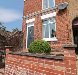 An outdoor view of a house with a door and windows at Moot Cottage in Driffield