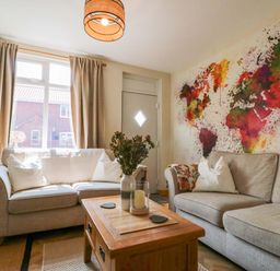 A living room with a couch, coffee table, and wall art at Moot Cottage in Driffield
