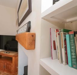 A living room with a bookshelf and television at Moot Cottage in Driffield